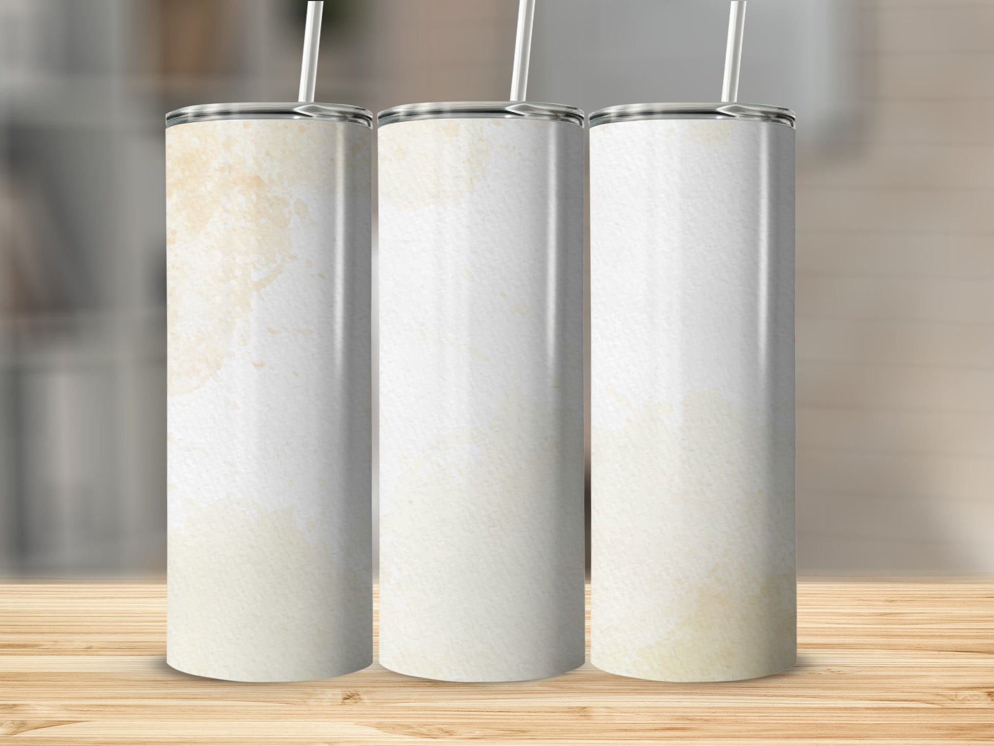 Three blank tumblers with a watercolor-like stain design on a wooden surface.