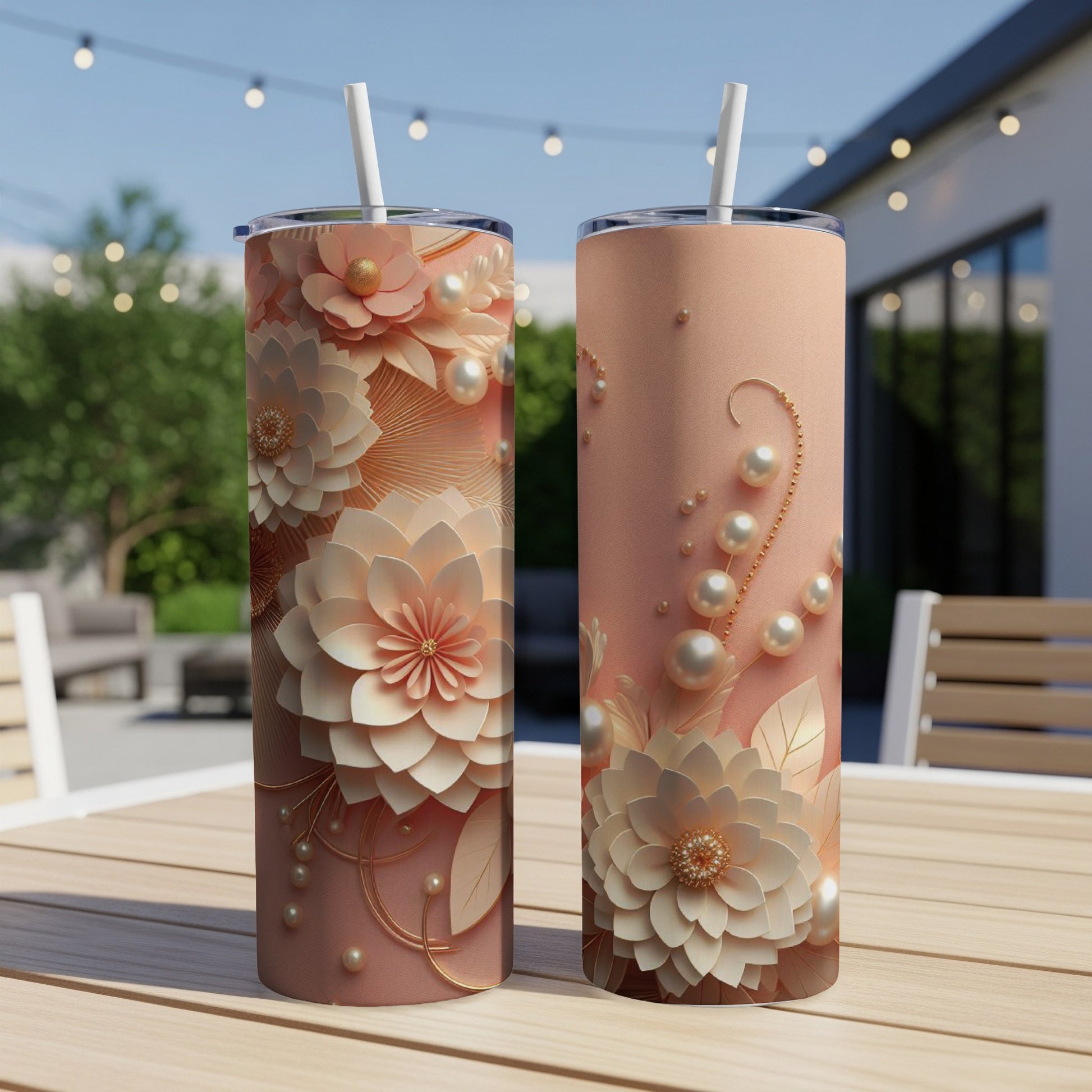 Two tall floral patterned tumblers with pearls and straws on a table outdoors.
