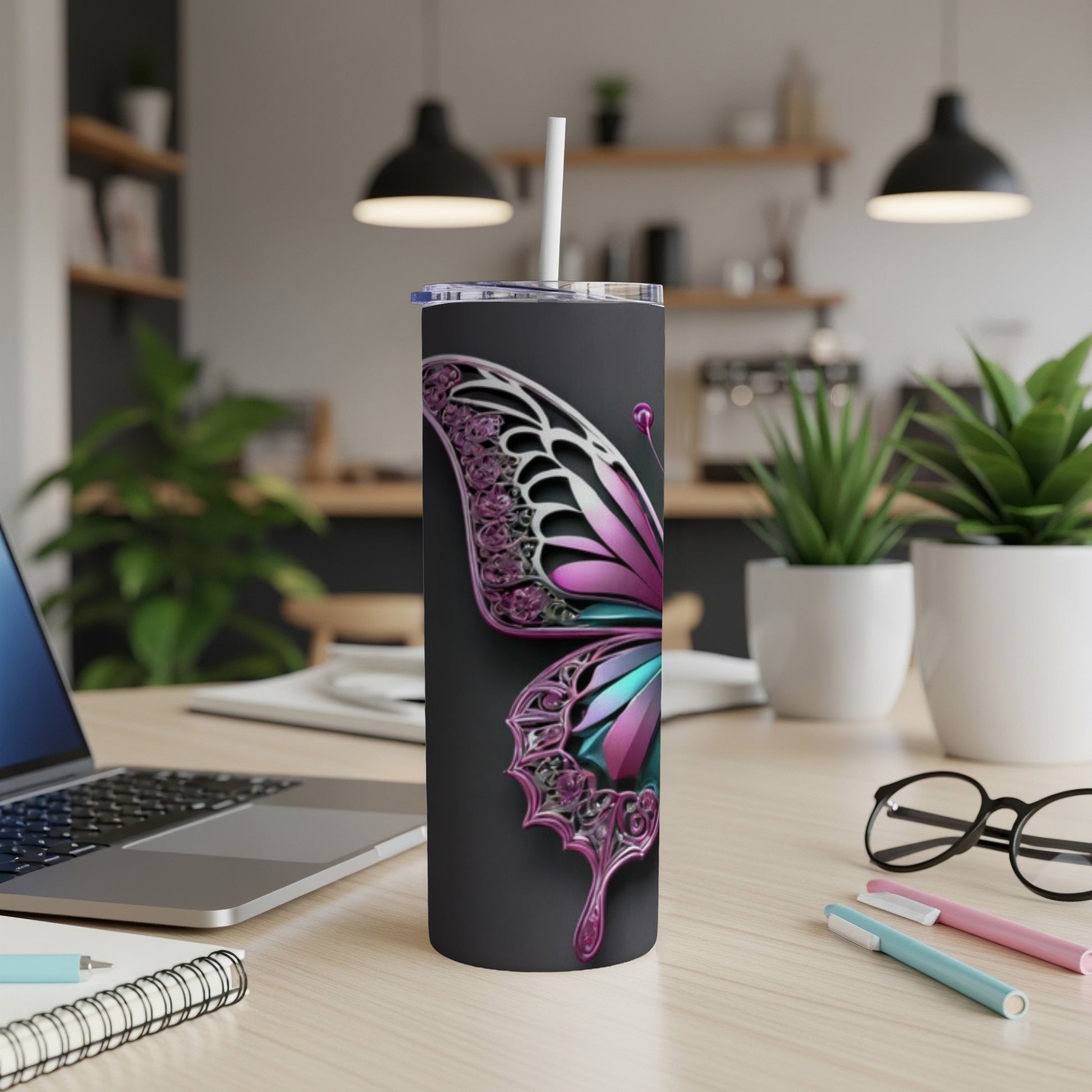 Black tumbler with a metallic butterfly design, straw, and laptop on desk.