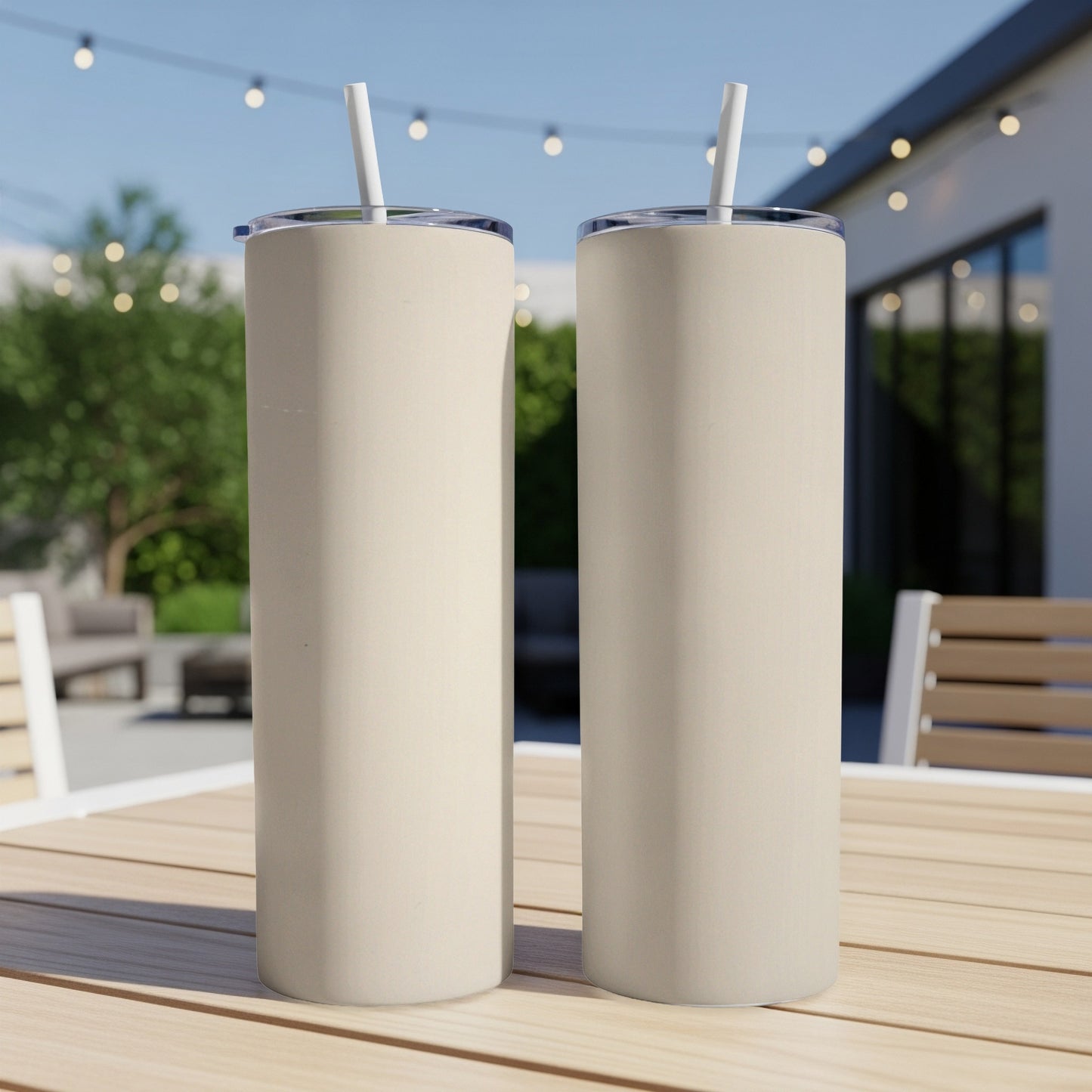 Two cream-colored tumblers with straws on a wooden table.