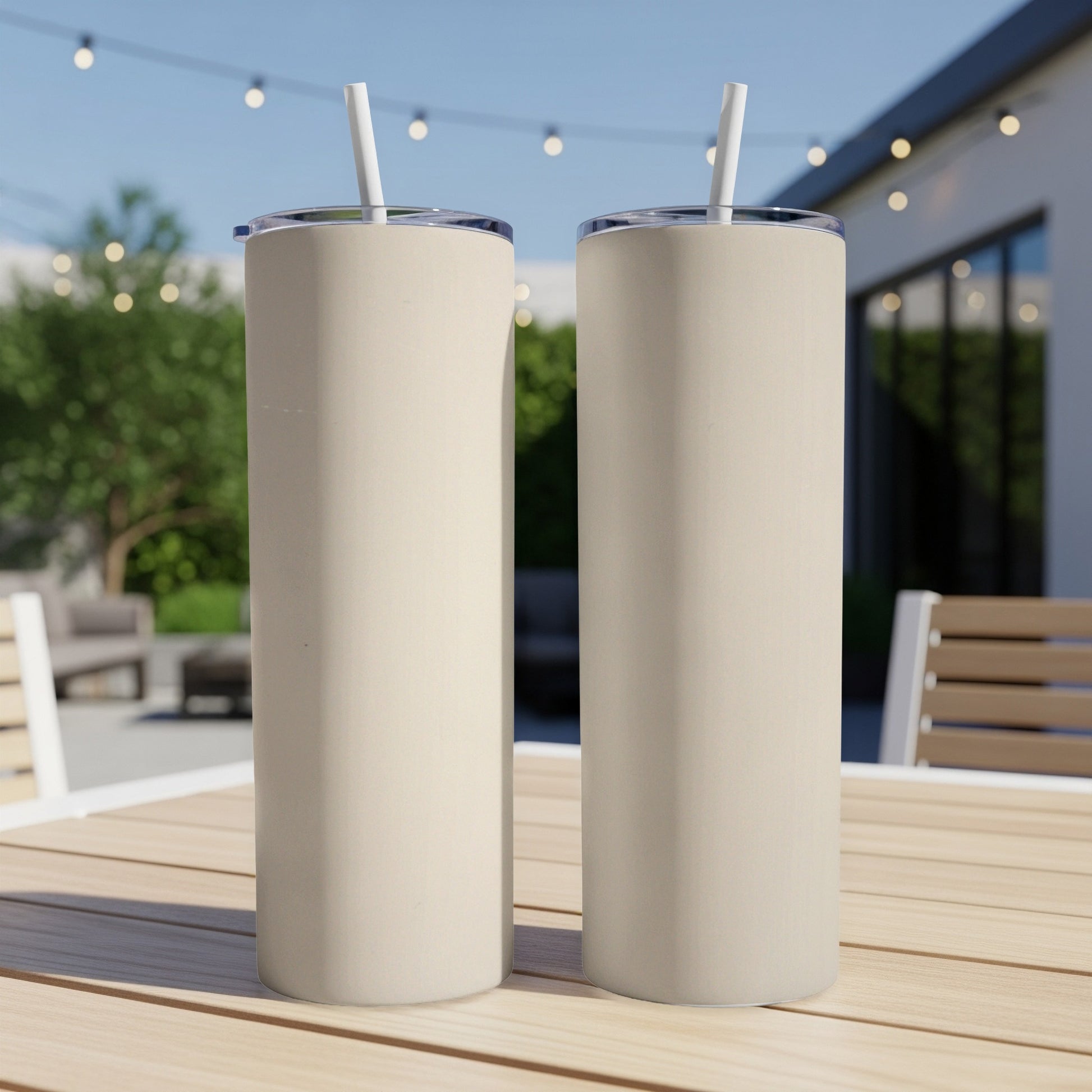 Two cream-colored tumblers with straws on a wooden table.
