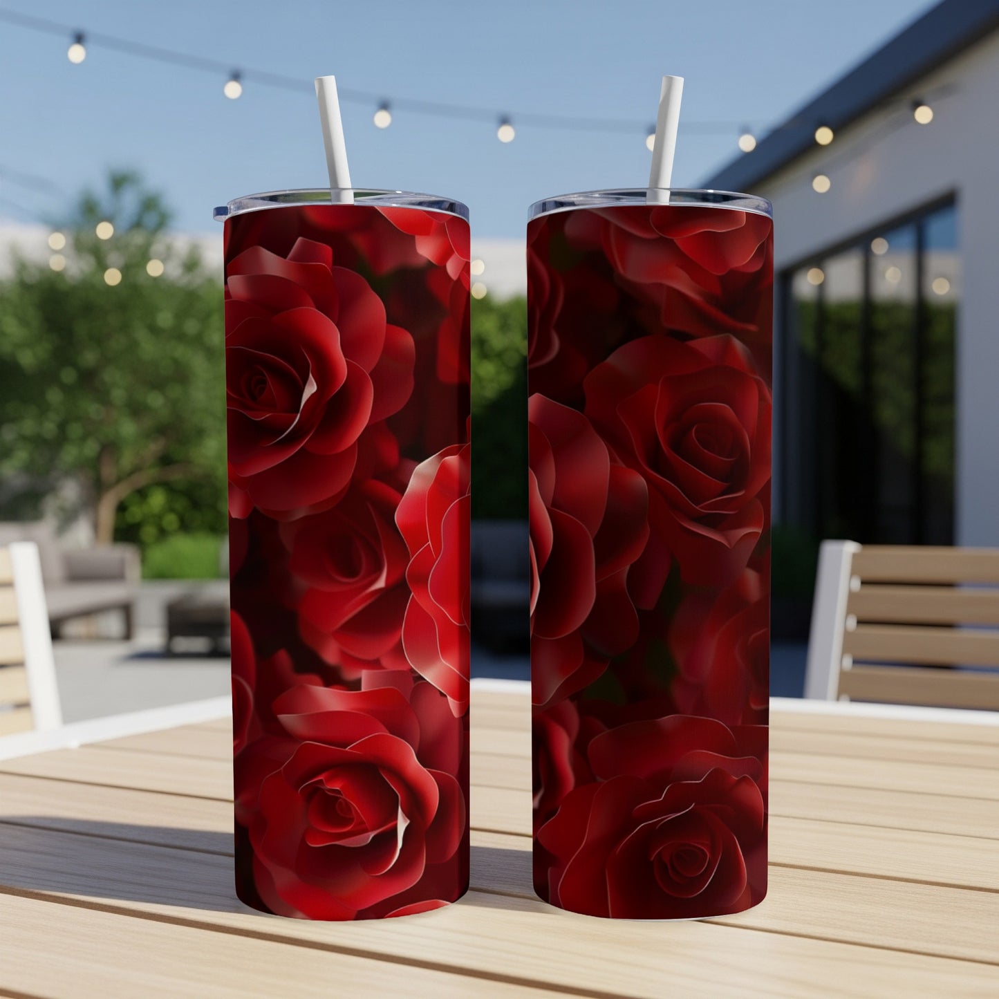 Two red rose patterned tumblers with straws on a table.