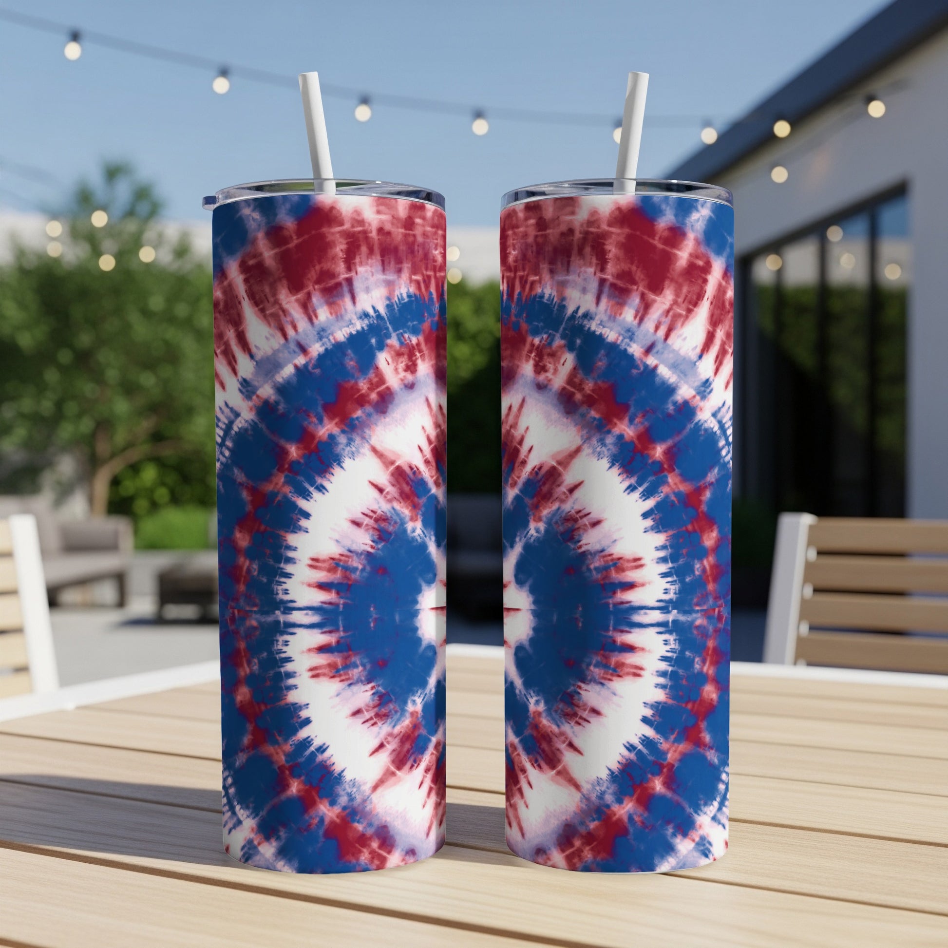Two tall tumblers with red, white, and blue tie-dye patterns sit on a wooden table.
