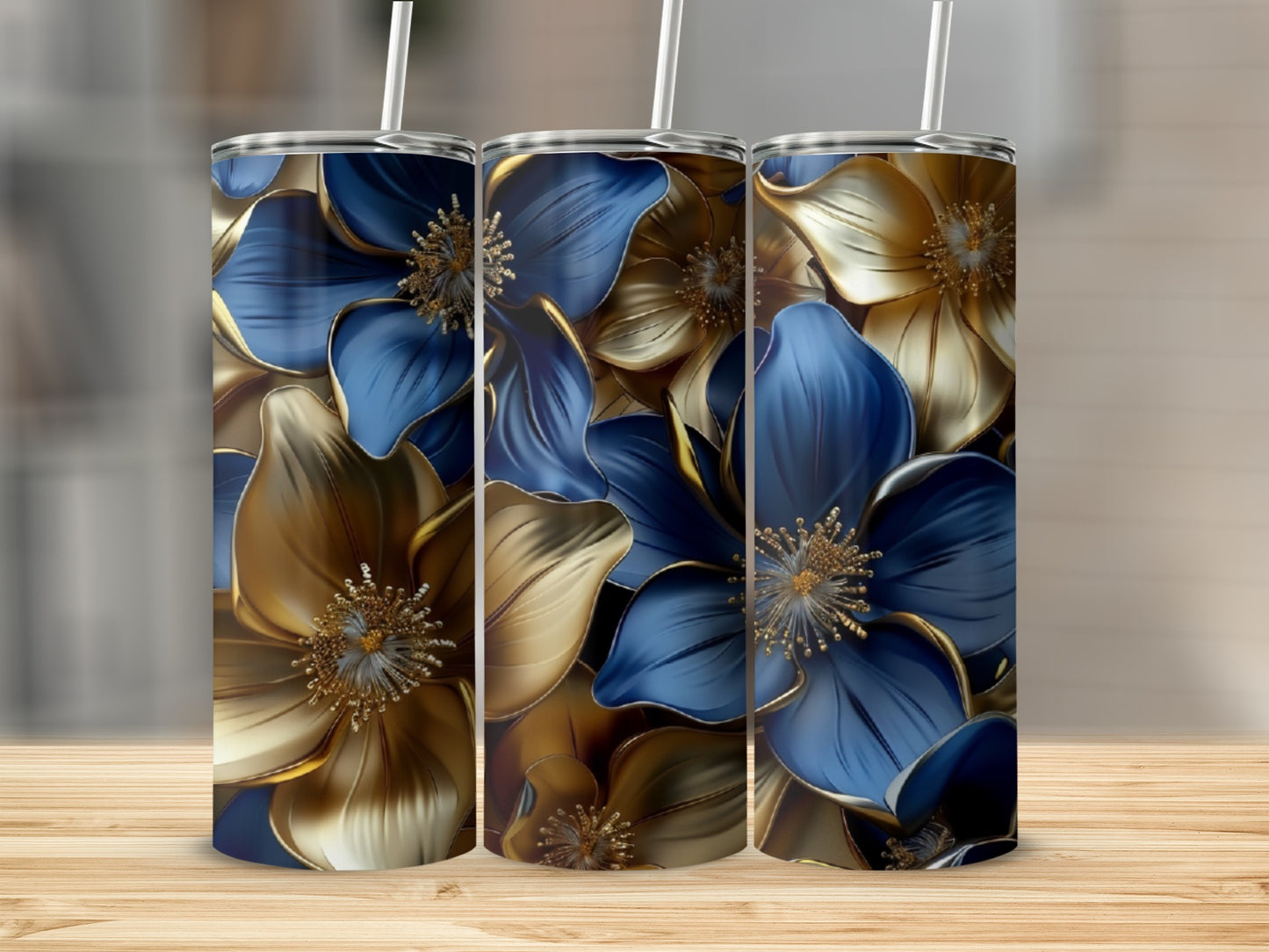 Three tumblers with gold and blue floral designs on a wooden surface.
