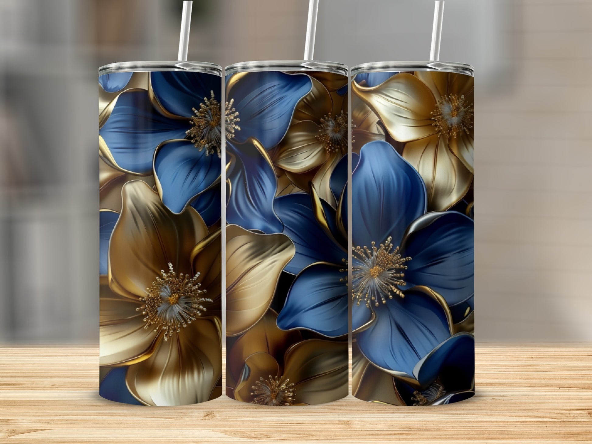 Three tumblers with gold and blue floral designs on a wooden surface.
