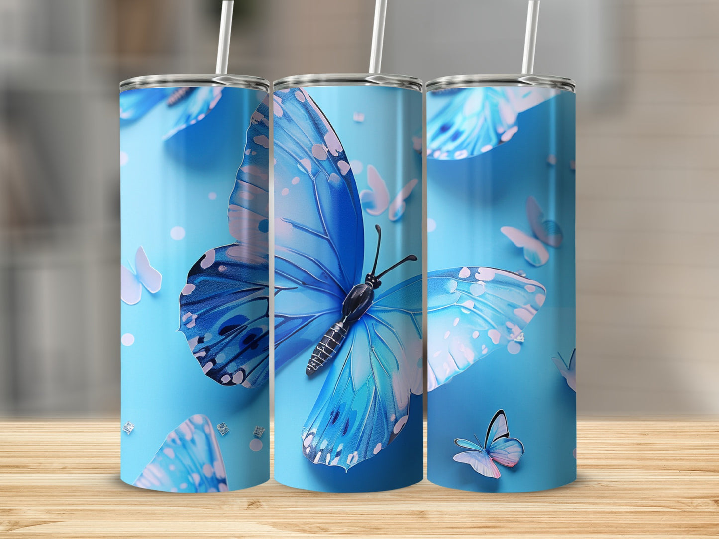 Three blue butterfly tumblers with straws against a light blue background.