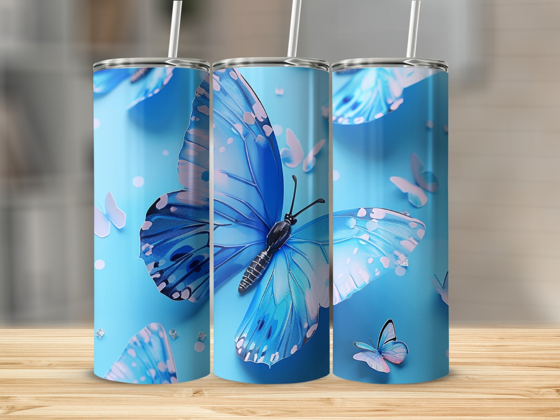 Three blue butterfly tumblers with straws against a light blue background.