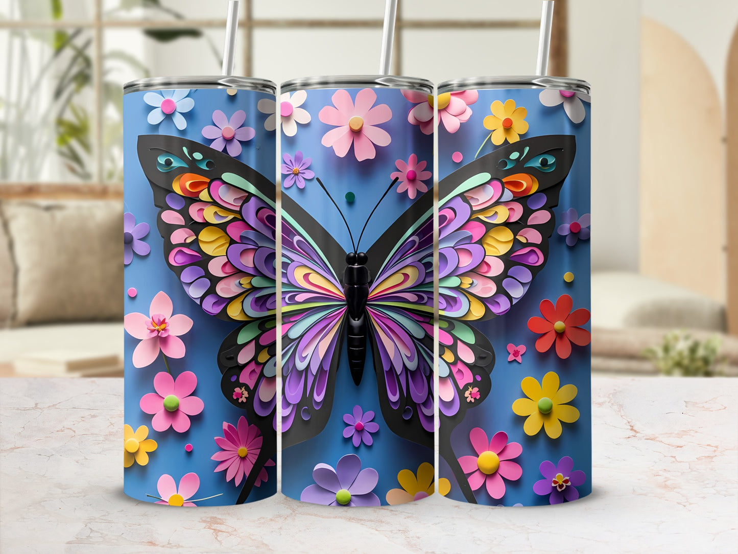 Three blue tumblers with colorful layered butterfly and flower designs.