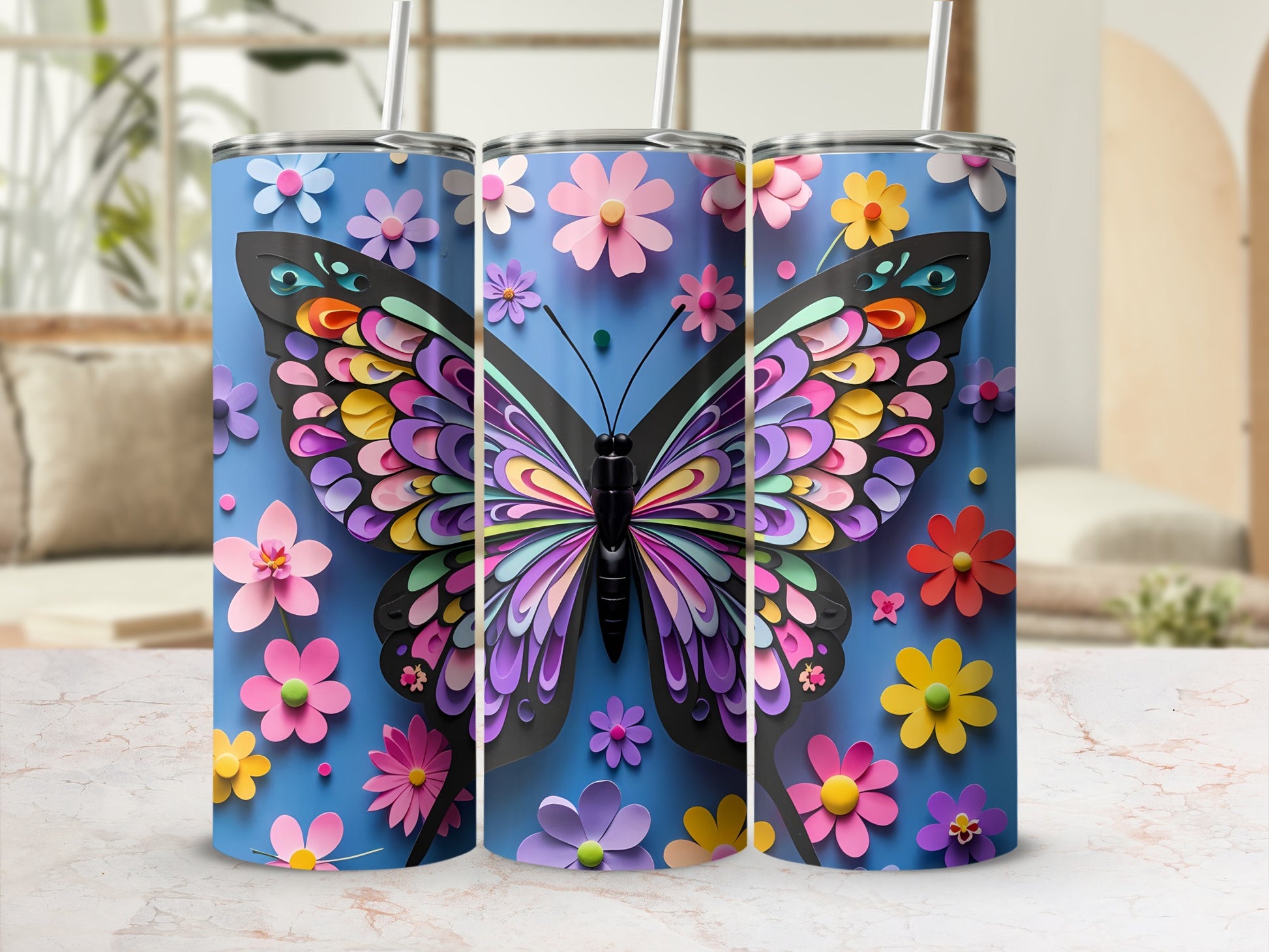 Three blue tumblers with colorful layered butterfly and flower designs.