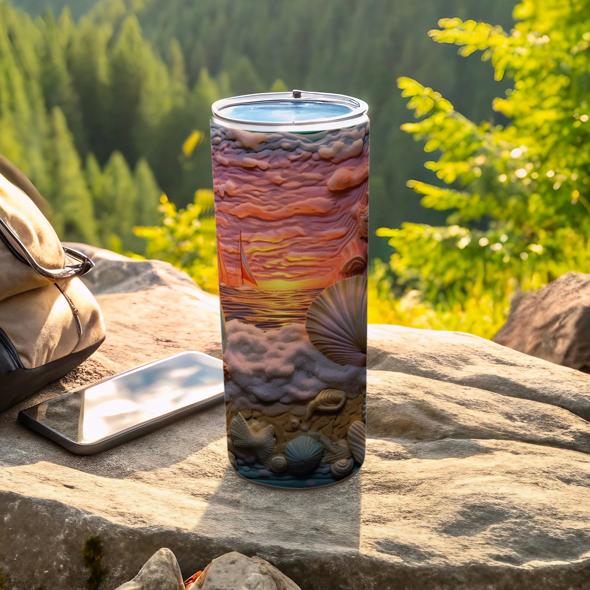 Tumbler with seashell and sailboat sunset design on rocky surface.