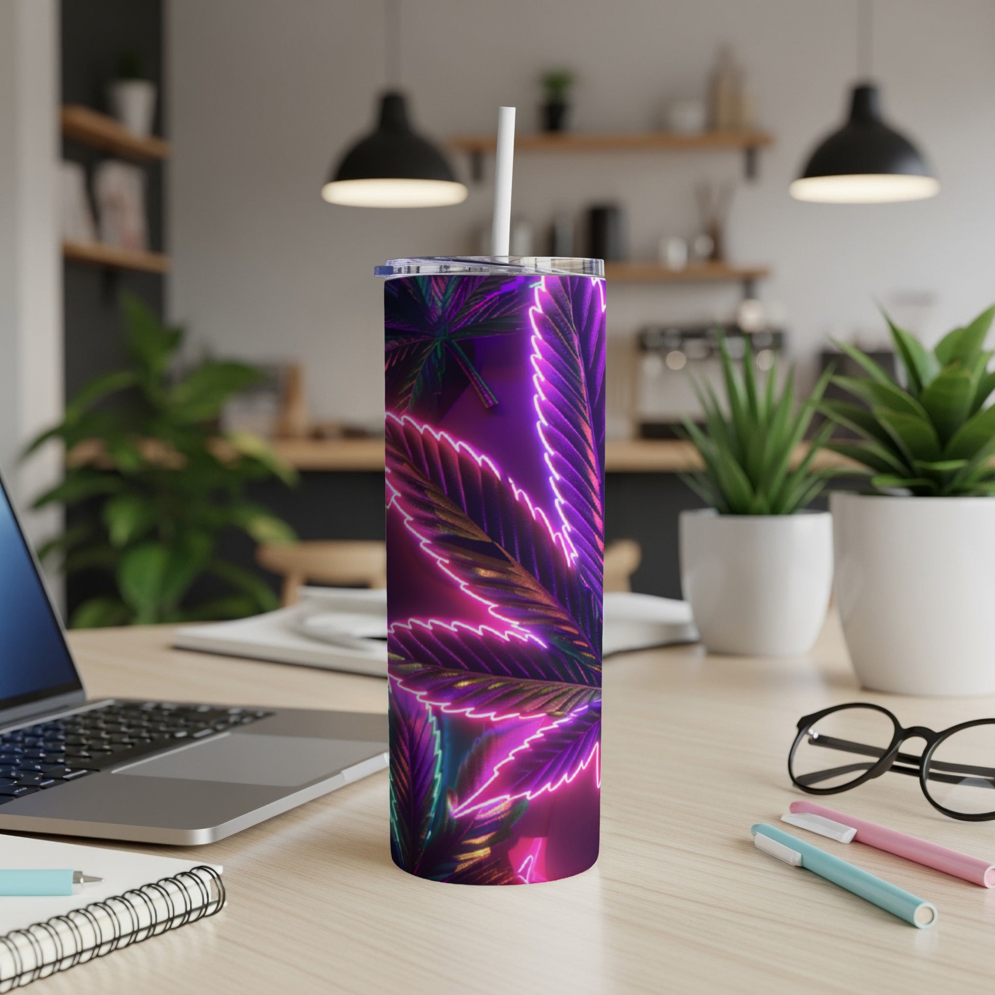 Tumbler with glowing neon purple cannabis leaf design on wooden desk.