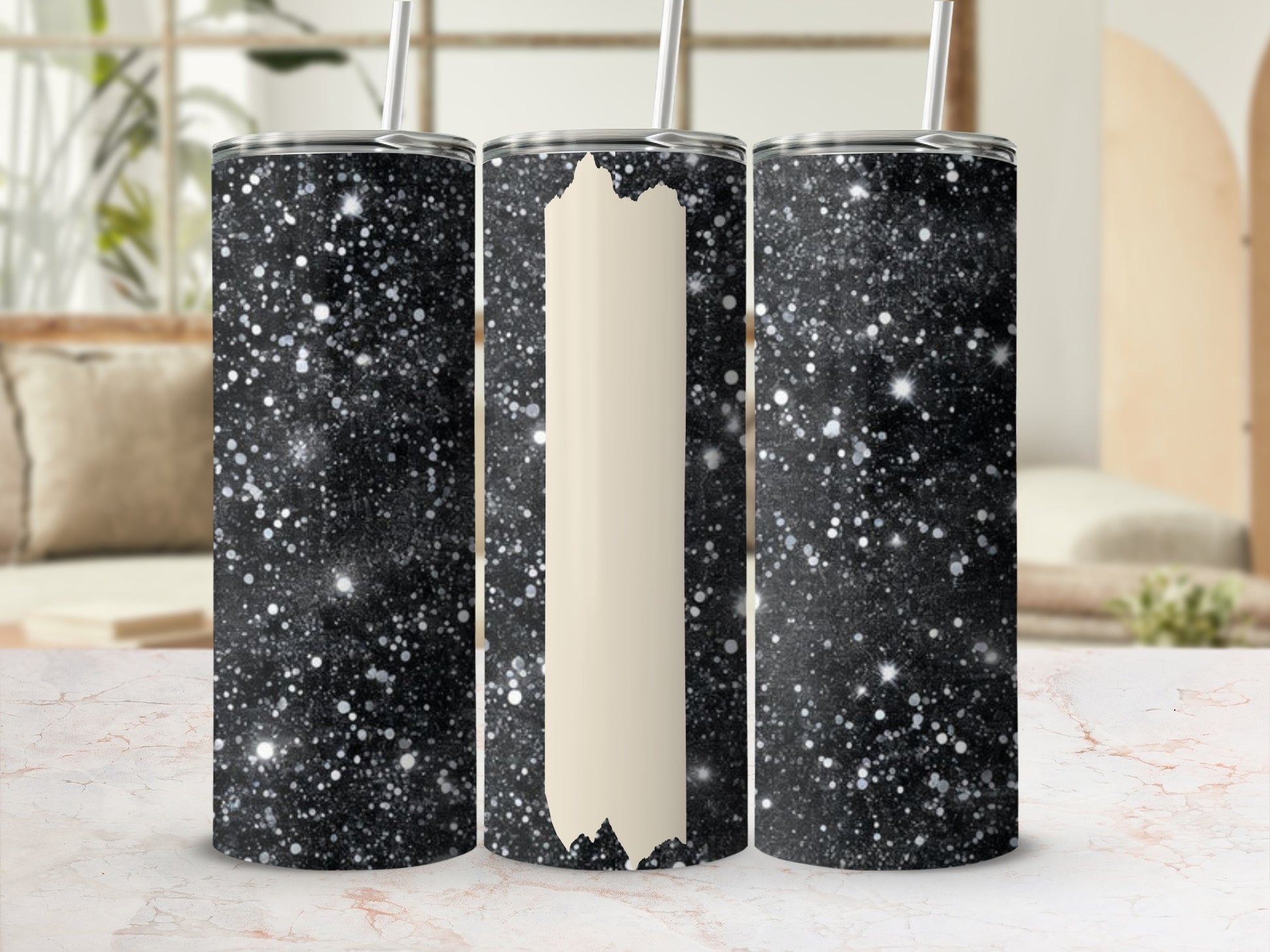 Three glittery black tumblers with straws on a marbled surface.