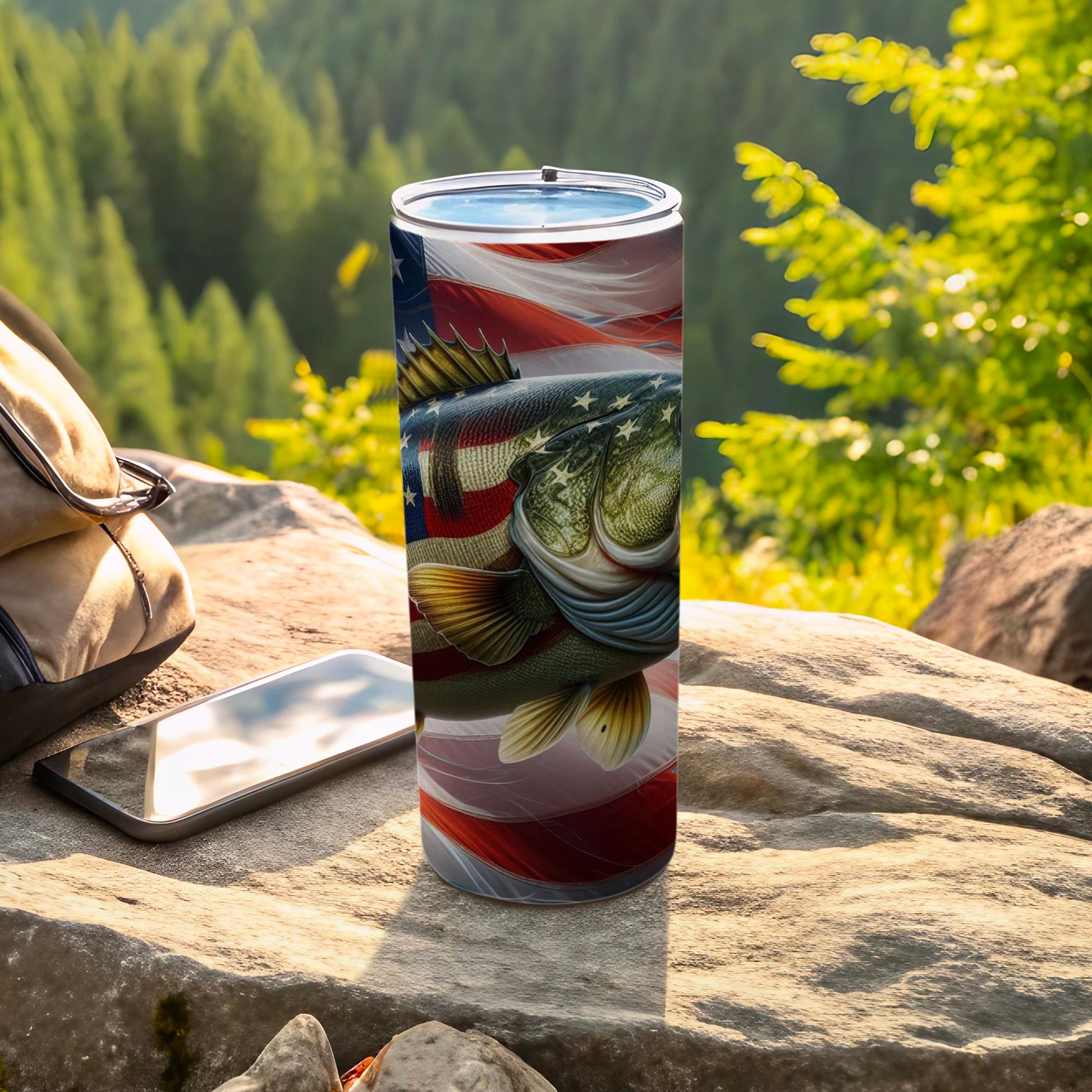 Bass fishing tumbler with American flag design, on rocks outdoors.