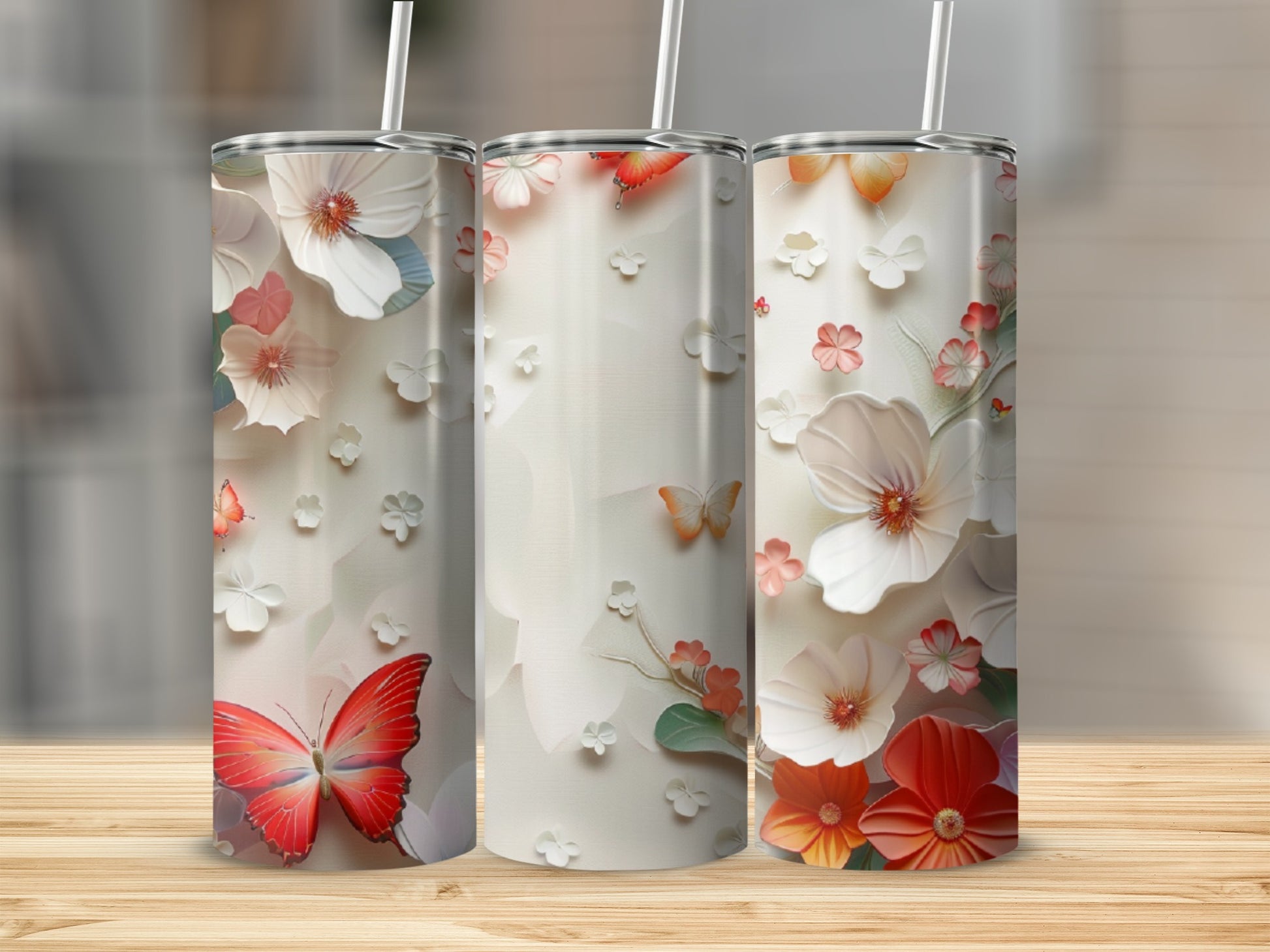 Three tumblers with floral and butterfly designs on a wooden surface.