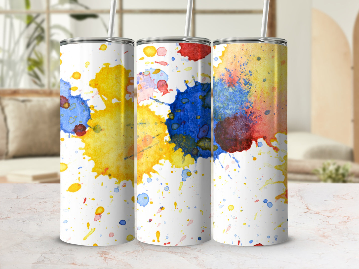 Three tumblers with colorful watercolor paint splatter designs.