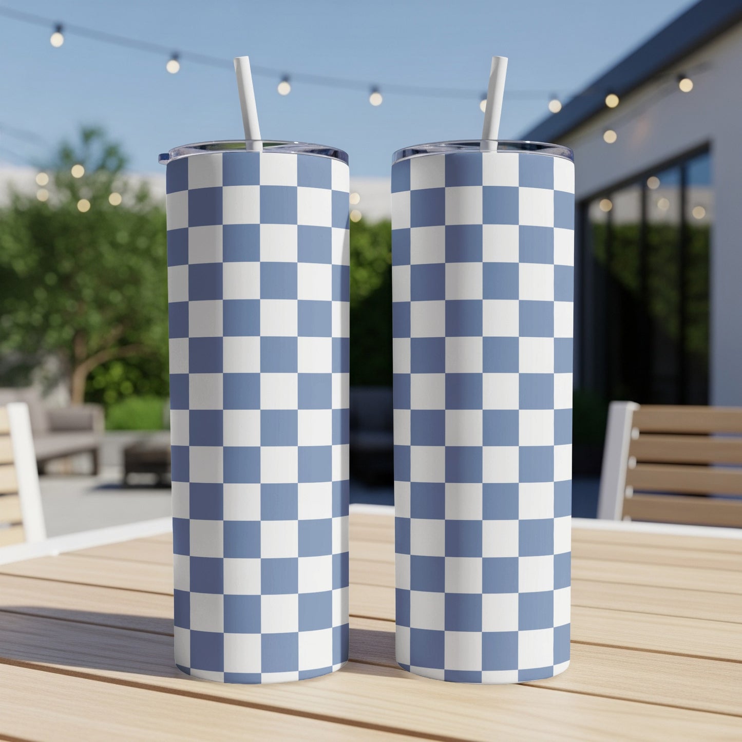 Two blue and white checkered tumblers with straws on a wooden table.