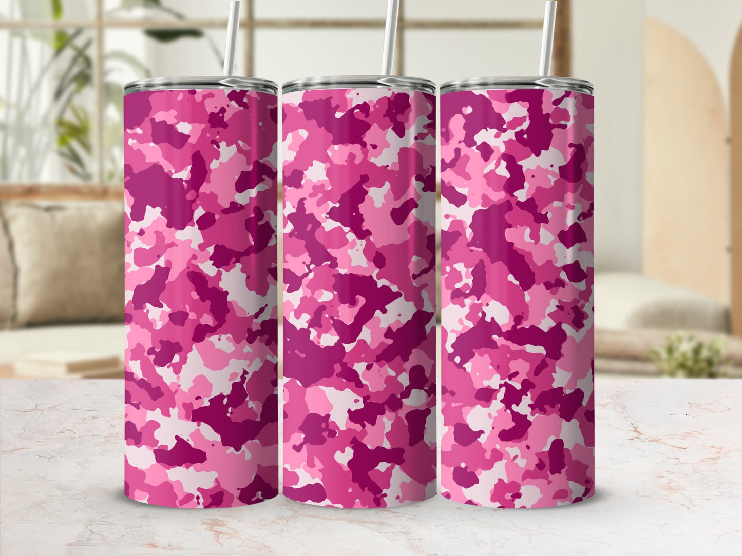 Three tumblers with pink camouflage pattern and straws on a marble surface.