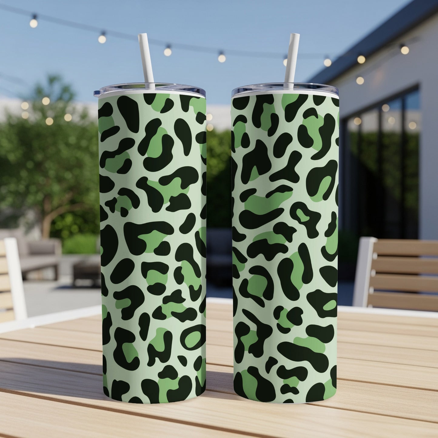 Two tall tumblers with green camouflage leopard print and white straws.