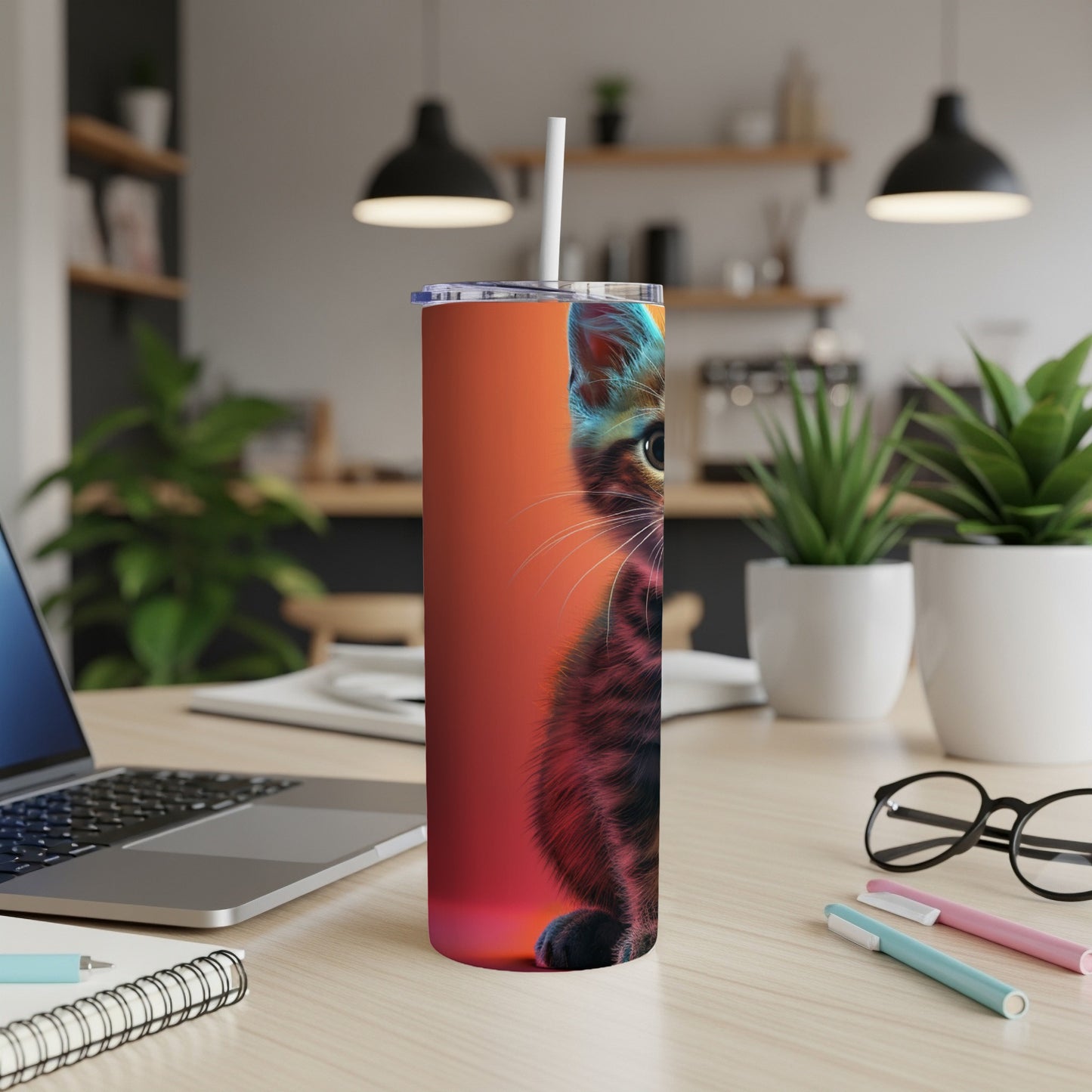Cat illustration on an orange tumbler with a straw, on a desk.