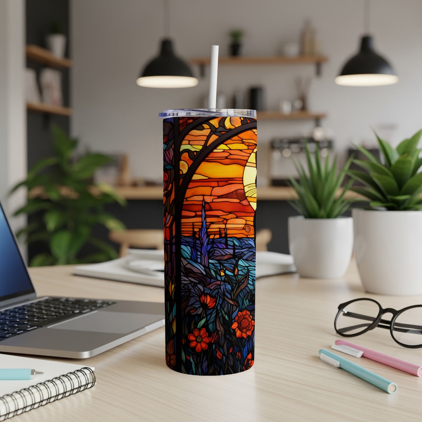 Tumbler with stained glass design of sunset, trees, and flowers.