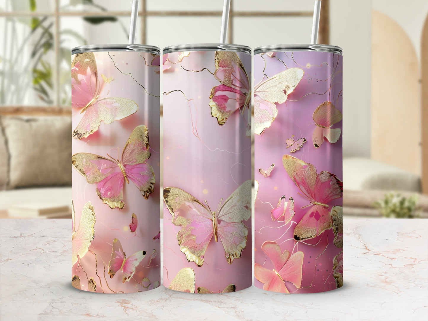 Three tumblers with pink butterflies and gold accents on a white marble surface.