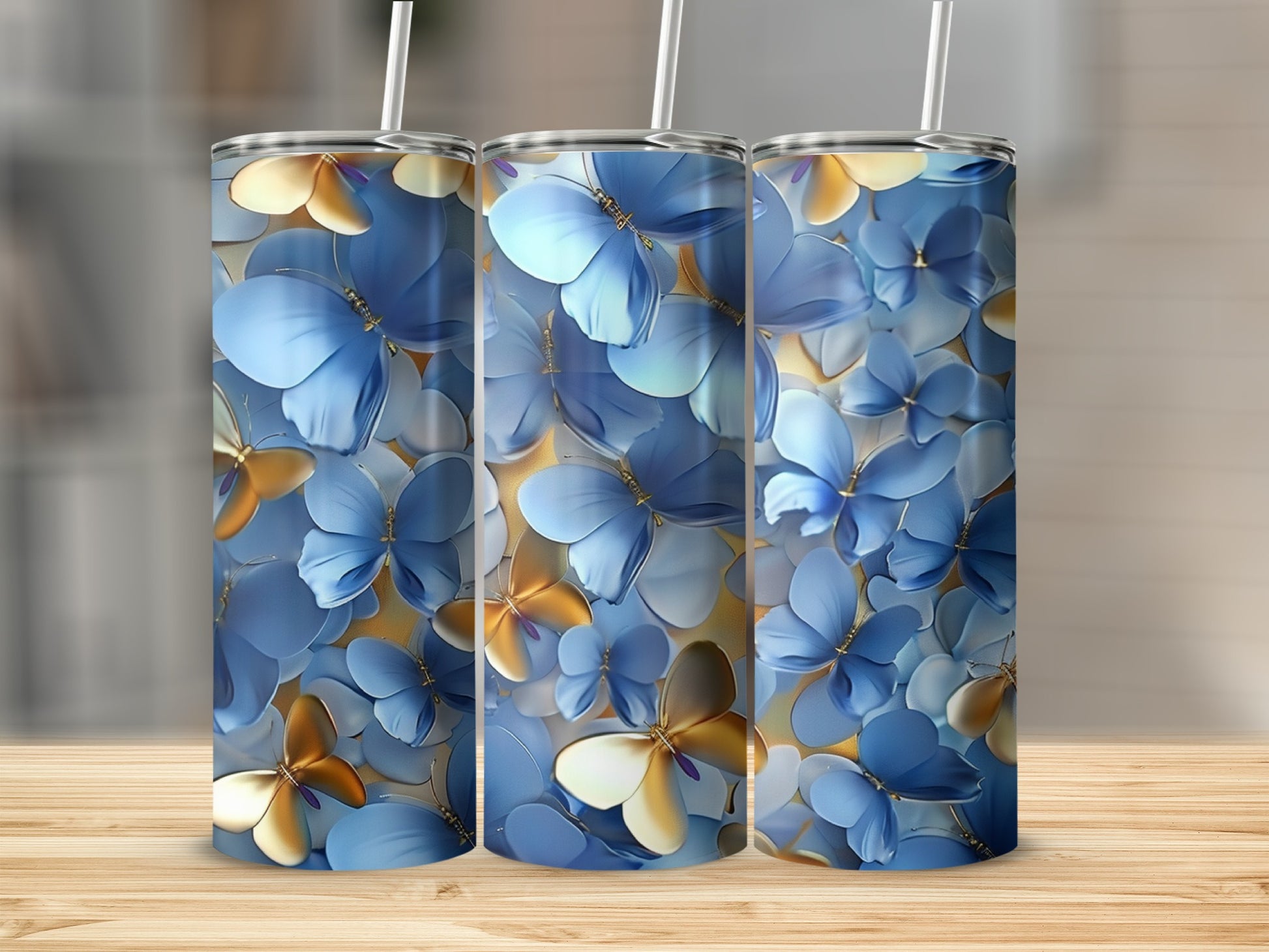Three blue and gold butterfly pattern tumblers on a wooden surface.