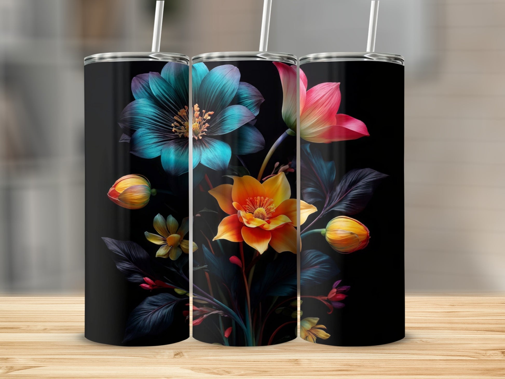 Three tumblers with vibrant floral designs on a wooden surface.
