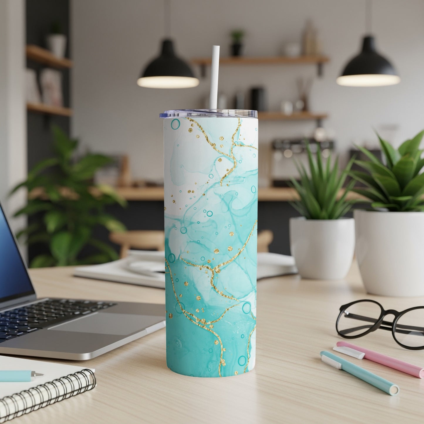 Teal and gold marble-patterned tumbler with straw on a desk.