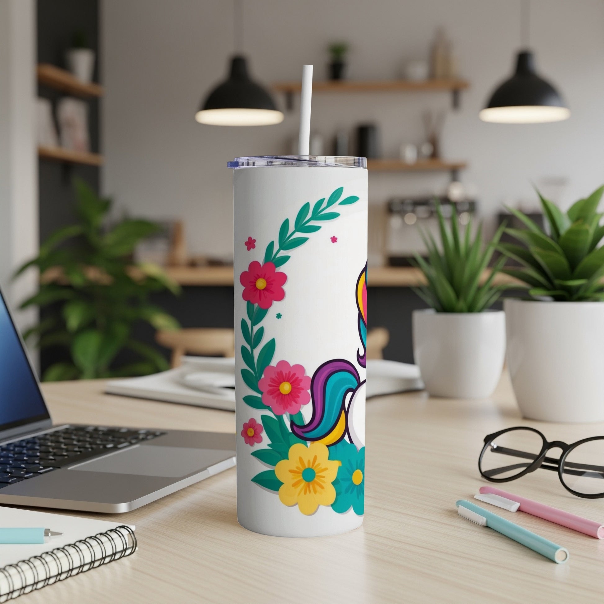 White tumbler with unicorn and floral design, straw inserted.