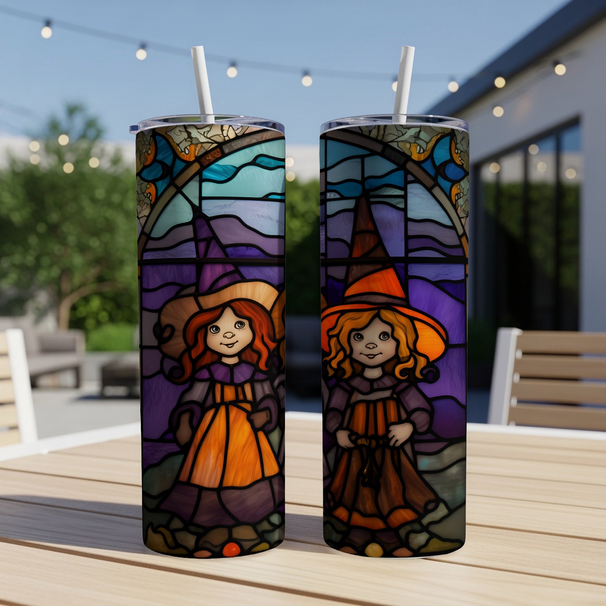 Two stained-glass style tumblers featuring cartoon witches on a patio table.