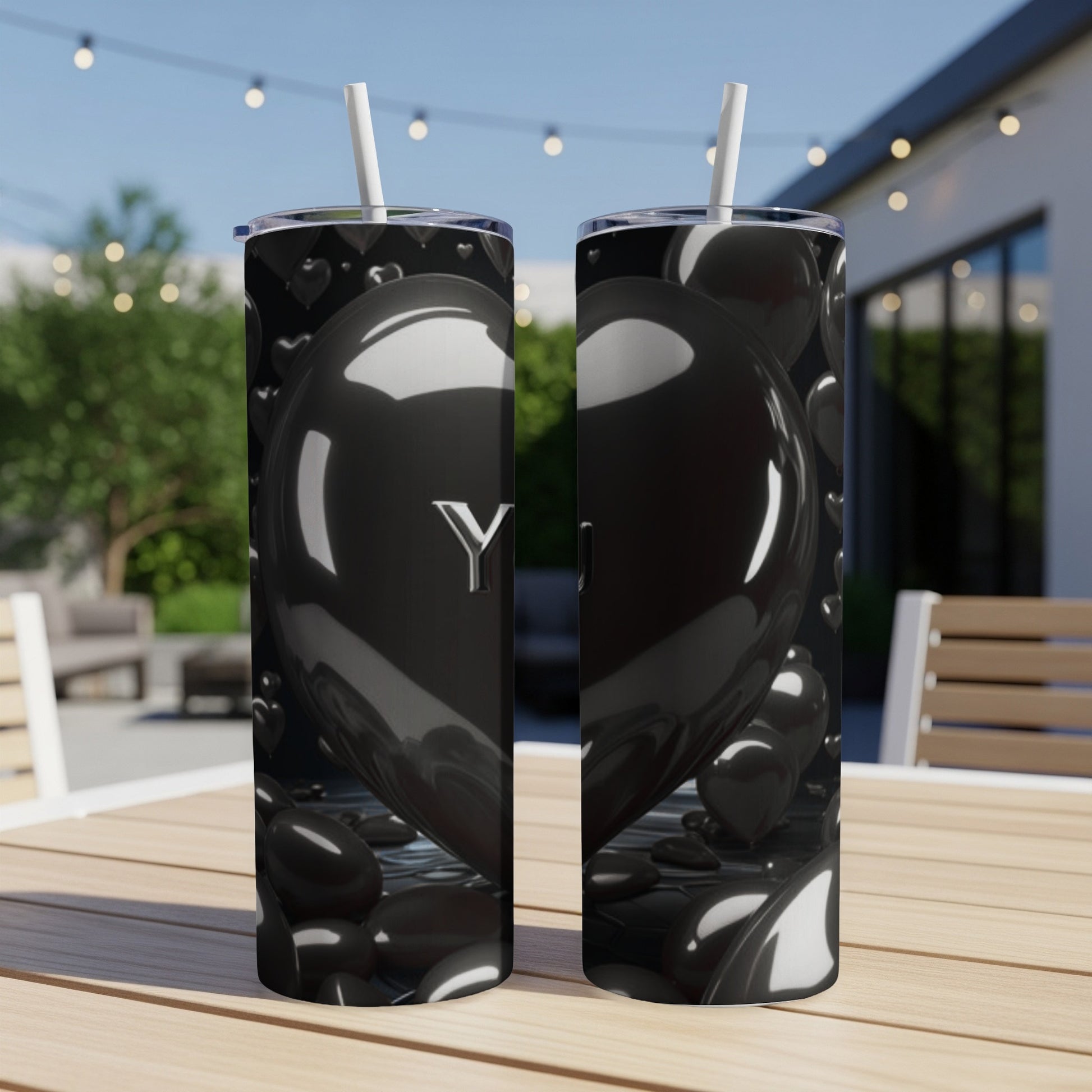 Black heart tumbler with "You" in silver lettering on a table outdoors.