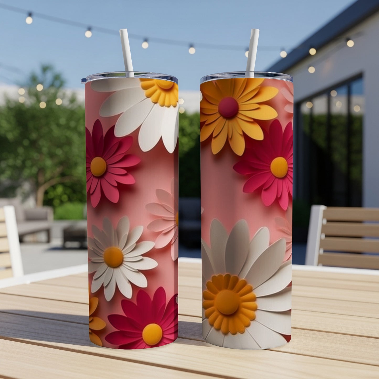 Two pink tumblers with colorful daisy designs sit on a table.