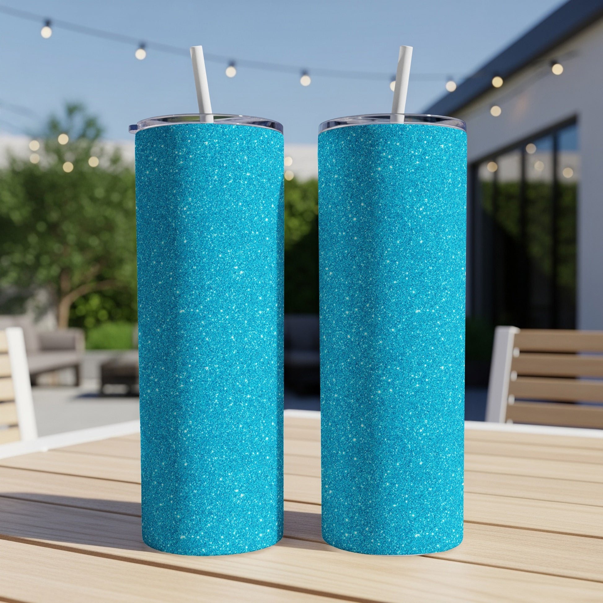 Two turquoise glitter tumblers with white straws on a wooden table.