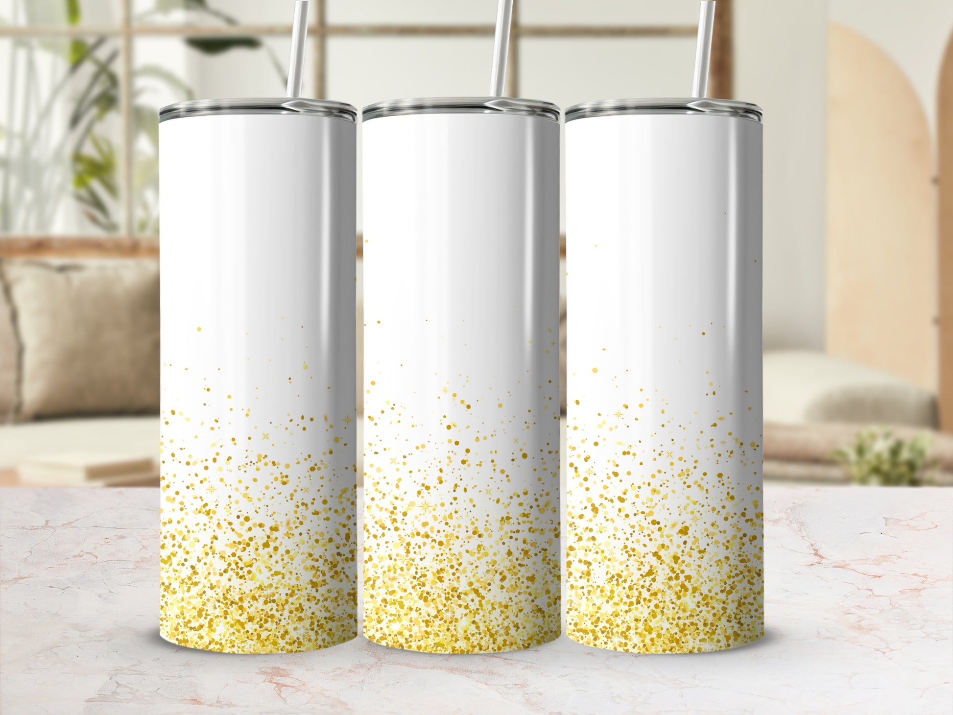 Three white tumblers with gold glitter speckles and straws.