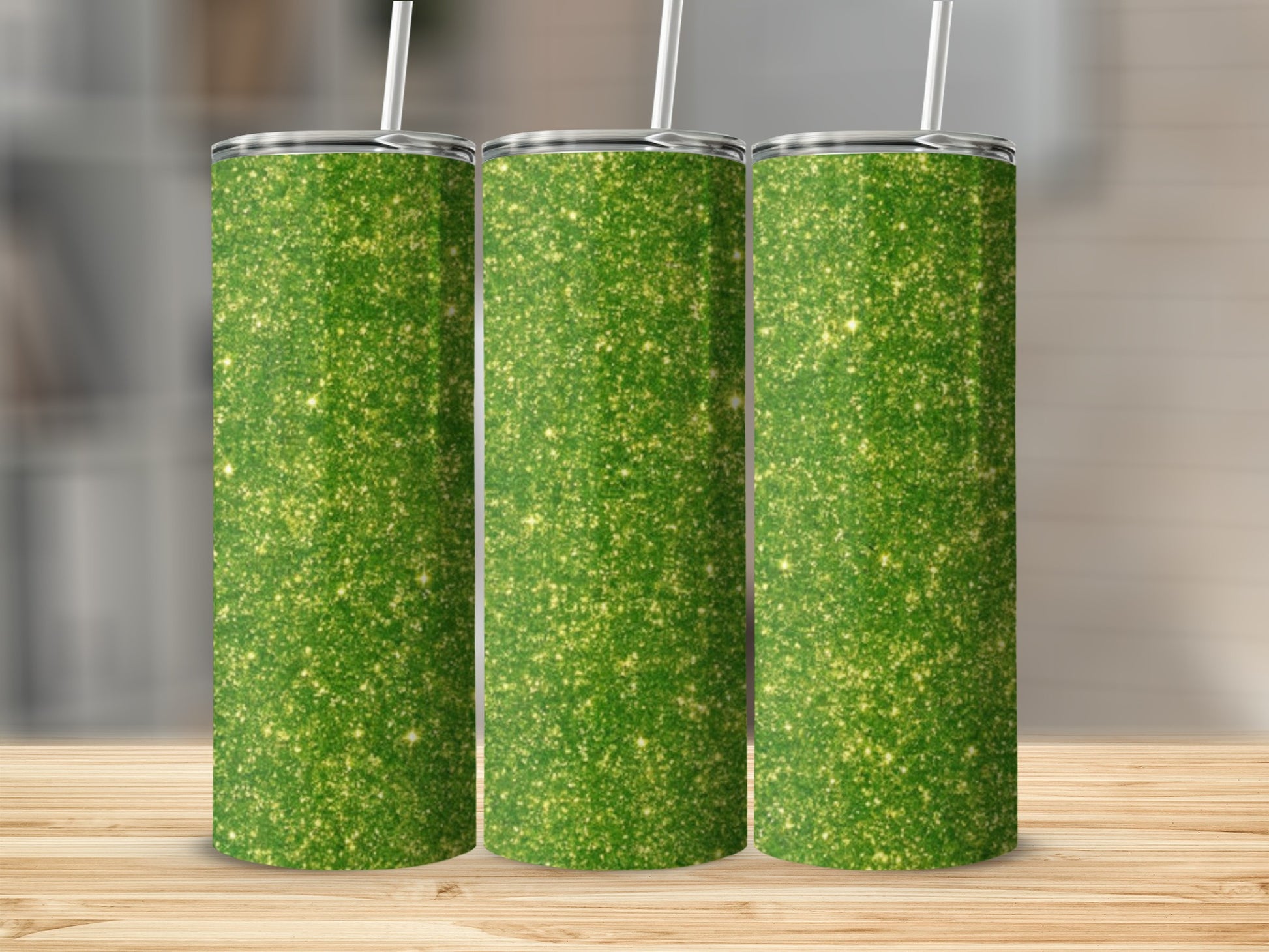 Three green glitter tumblers with white straws on a wooden surface.