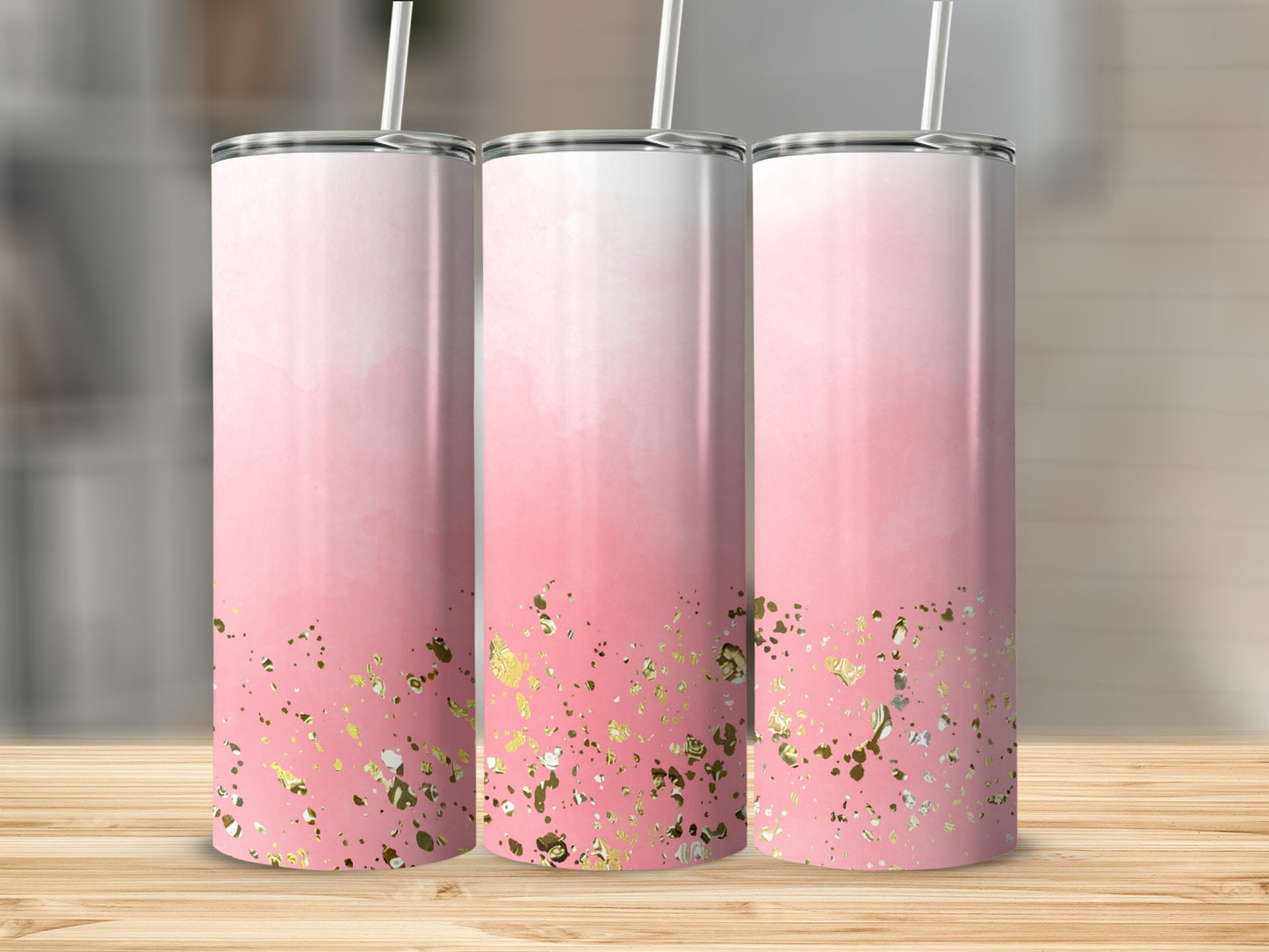 Three pink gradient tumblers with gold glitter accents on a wooden surface.