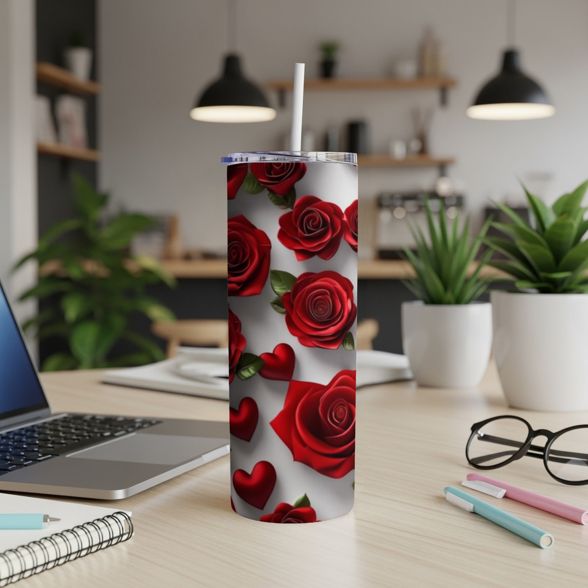 White tumbler with red roses and hearts, standing on a desk.