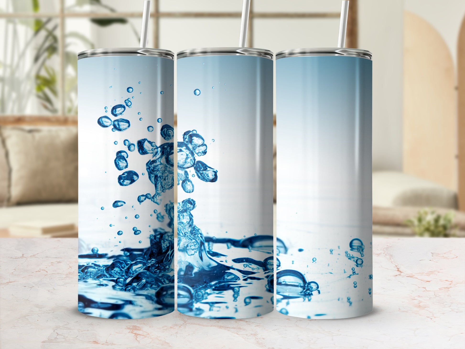Three tumblers with blue water splash designs on a marble surface.