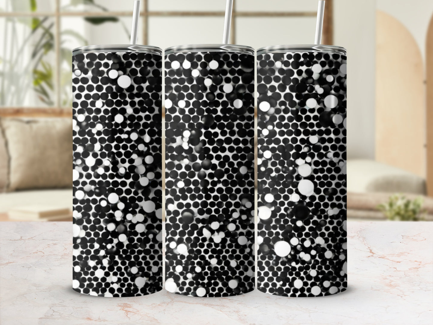 Three tumblers with a black and white bubbly pattern stand on a marble surface.