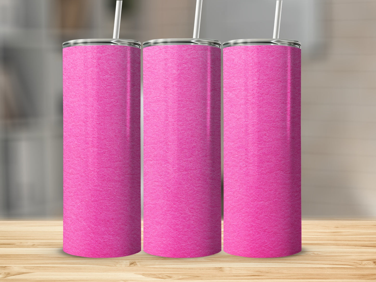 Three blank pink tumblers with straws stand on a wooden surface.