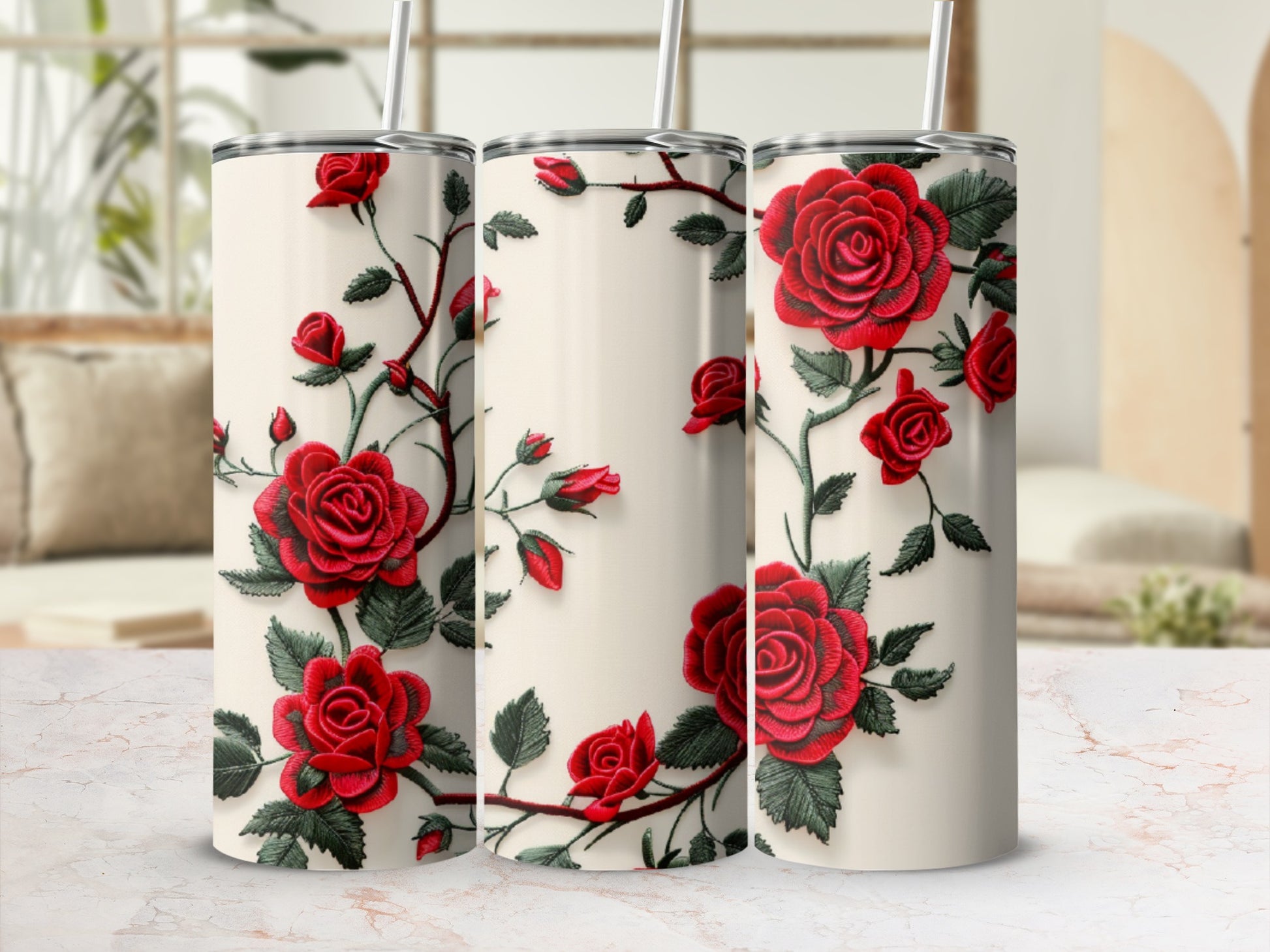 Three cream tumblers with red rose and vine design, on a marbled surface.