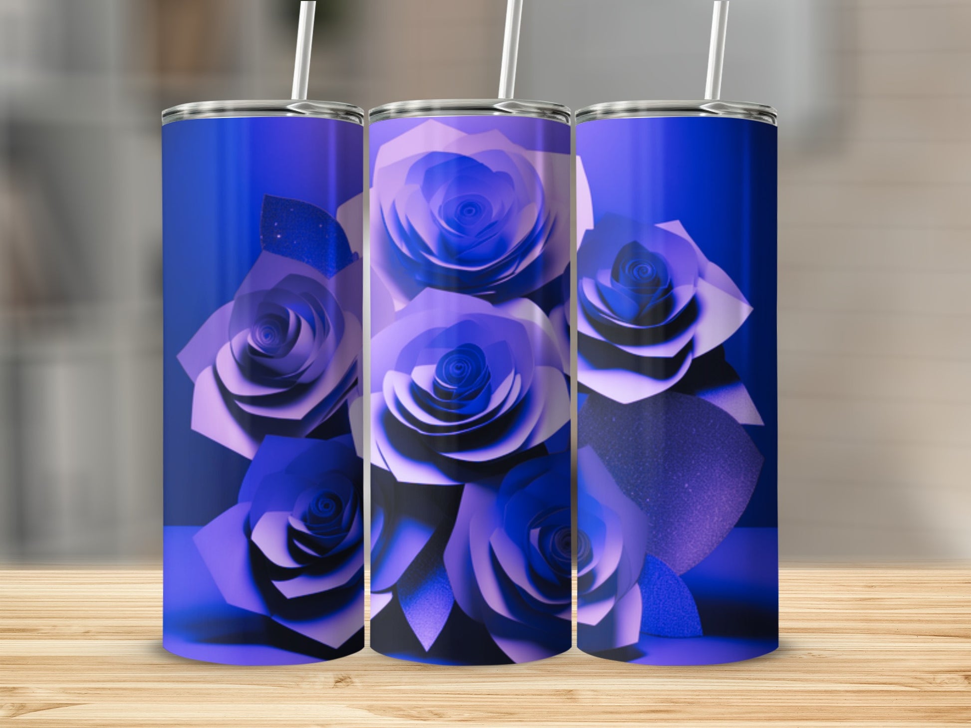 Three blue tumblers with paper rose designs stand on a wooden surface.