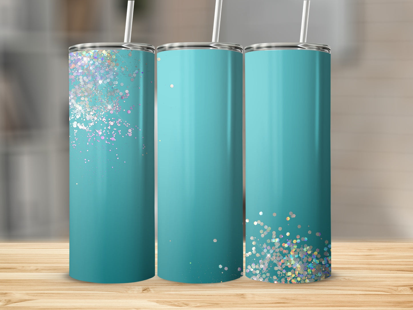 Three teal tumblers with glitter accents are displayed on a wooden surface.