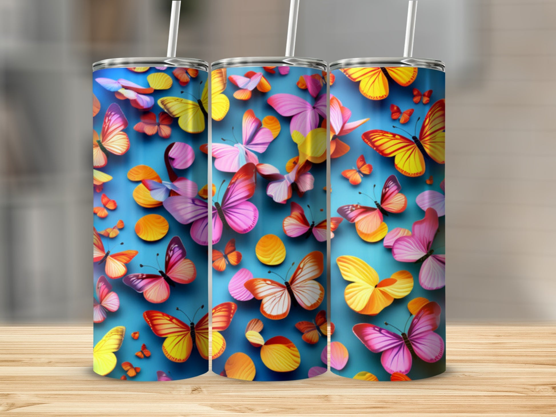 Three tumblers with colorful butterfly designs on a blue background.
