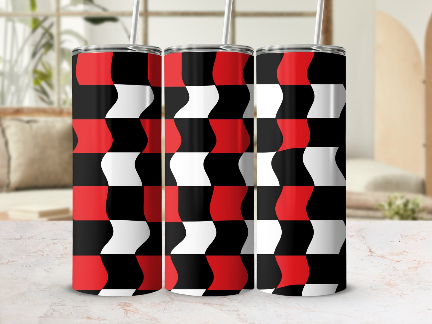 Three red, black, and white geometric pattern tumblers with straws on a marble surface.