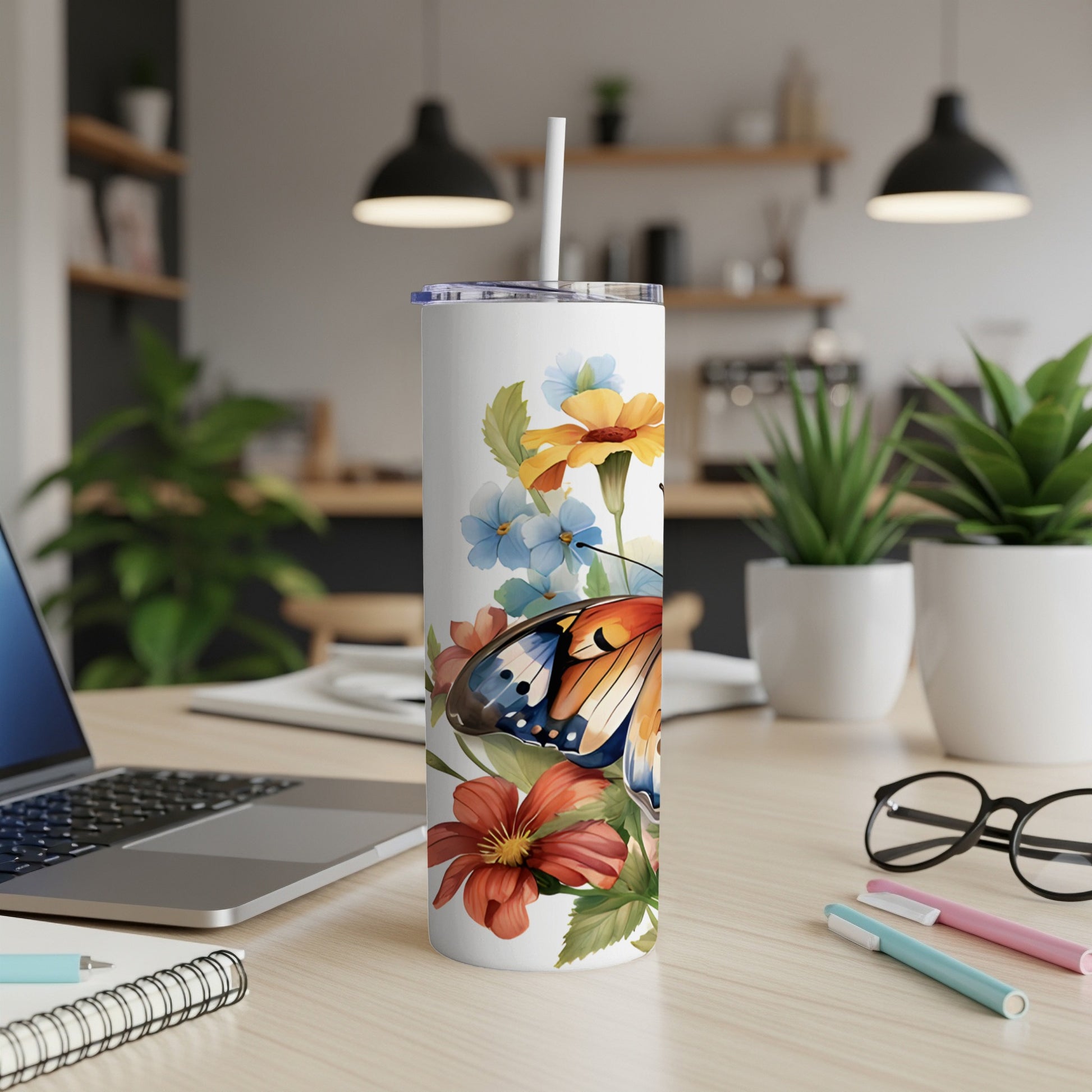 White tumbler with butterfly and floral design, featuring a straw.