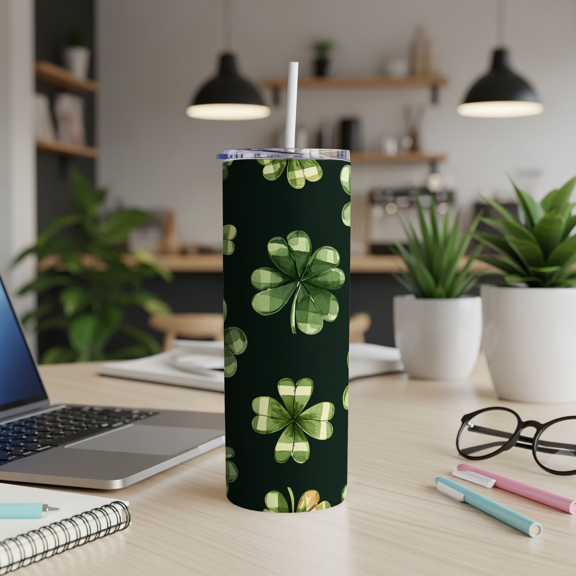 Green plaid shamrocks pattern on dark tumbler with straw, on desk.