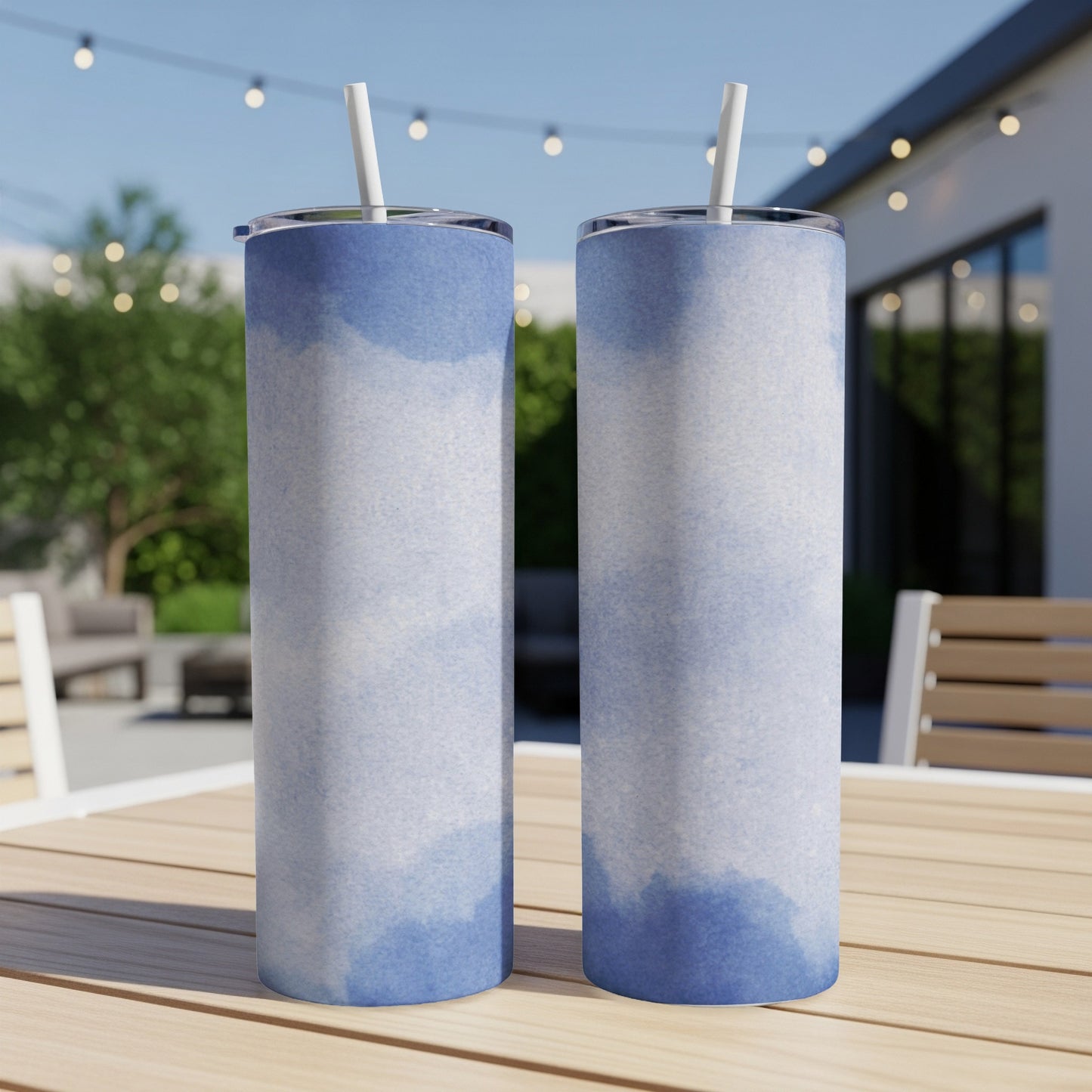 Two tall tumblers with blue watercolor patterns and straws on a table.