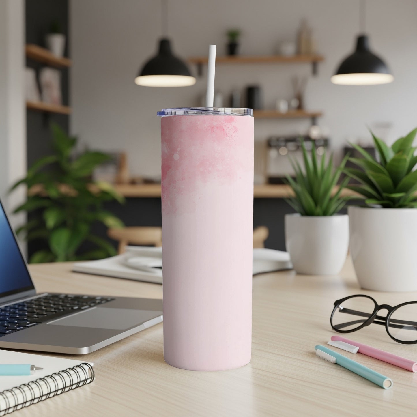 Pink watercolor tumbler with straw on desk with laptop and pens.