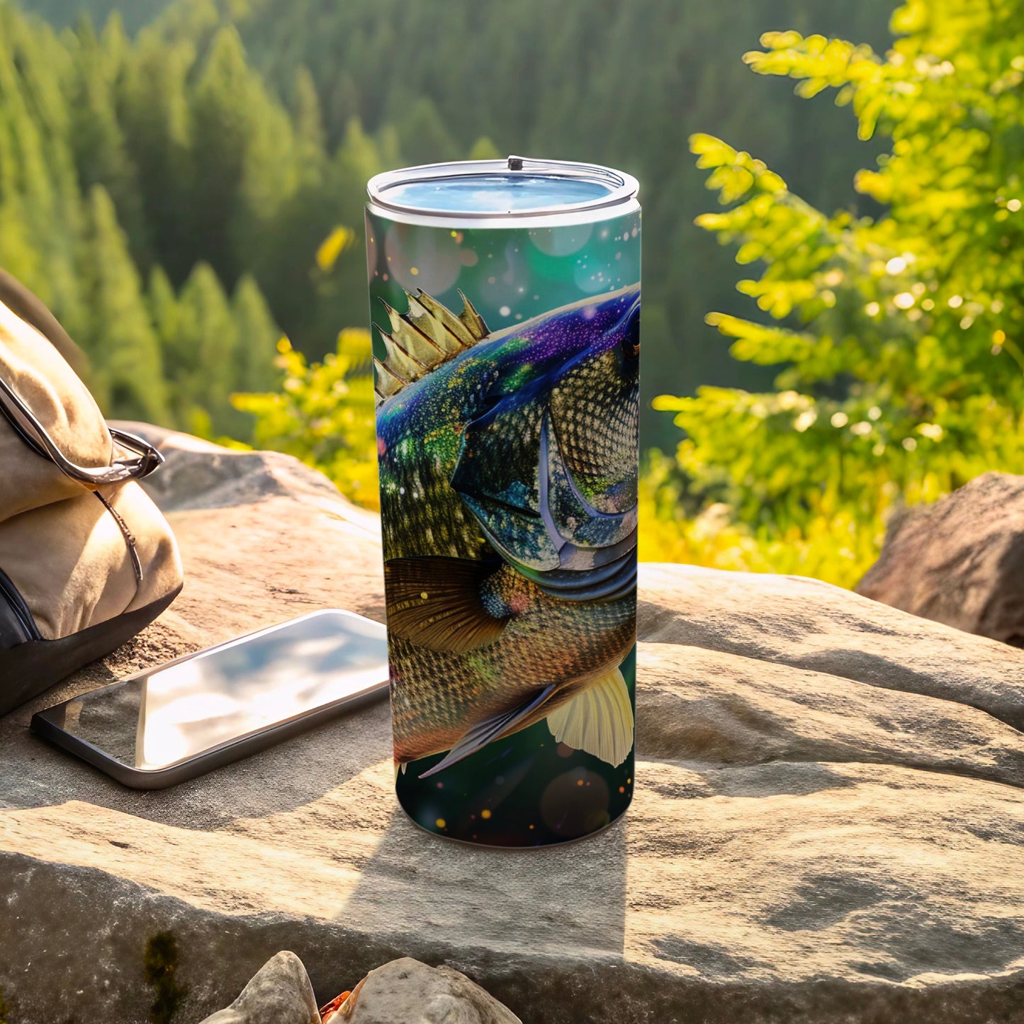 Stainless steel tumbler with a detailed fish graphic, resting on rocks outdoors.